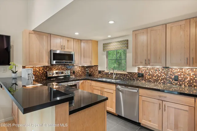 a kitchen with stainless steel appliances granite countertop a sink stove and microwave