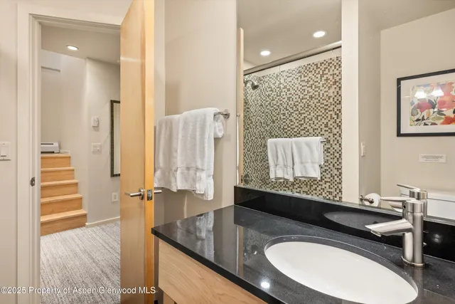 a bathroom with a granite countertop sink a mirror and a shower