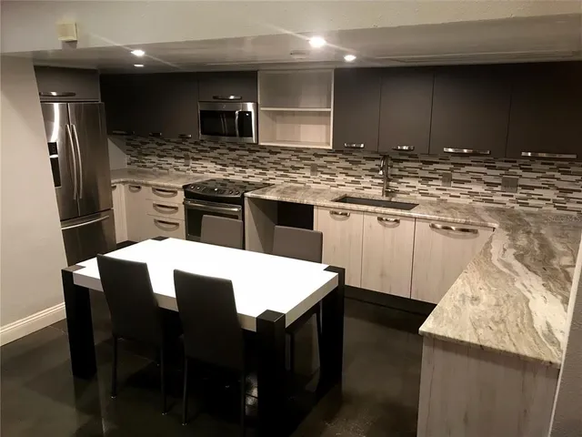 a kitchen with stainless steel appliances kitchen island granite countertop a sink stove and refrigerator