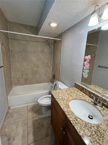 a bathroom with a granite countertop sink a toilet and bathtub