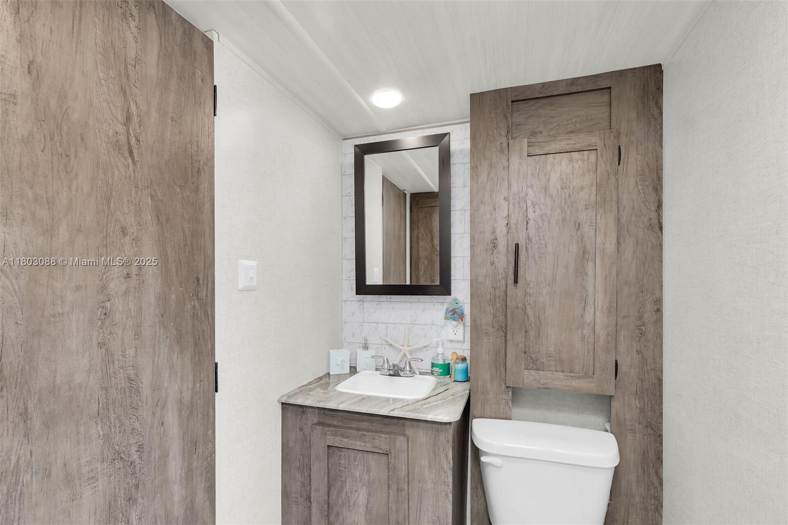 325 Calusa Street Key Largo, FL 33037 - Photo 28 of 34 a bathroom with a toilet a sink a mirror and vanity