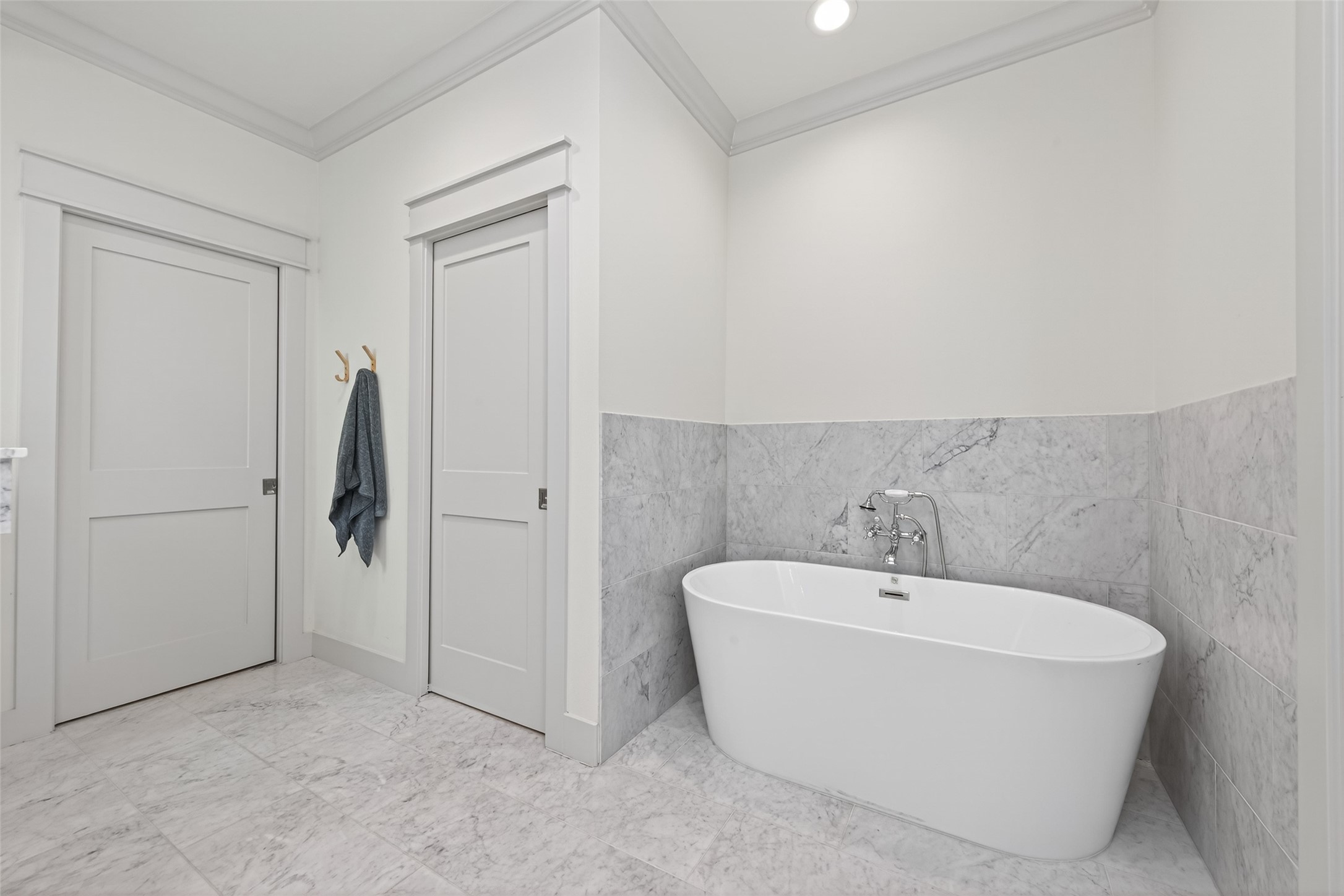 515 West 25th Street Houston, TX 77008 - Photo 19 of 35 Spa-like 11’1” x 12’ primary bathroom features a UPC 60” x 42” soaking tub with white Carrara marble 12” x 24” tile surround, a frameless glass shower with matching Carrara marble tile and a built-in bench, and a frosted clerestory window that brings in soft natural light. The water closet includes a Kohler toilet and an extra storage cabinet, all complemented by elegant white Carrara marble 12” x 24” tile flooring.