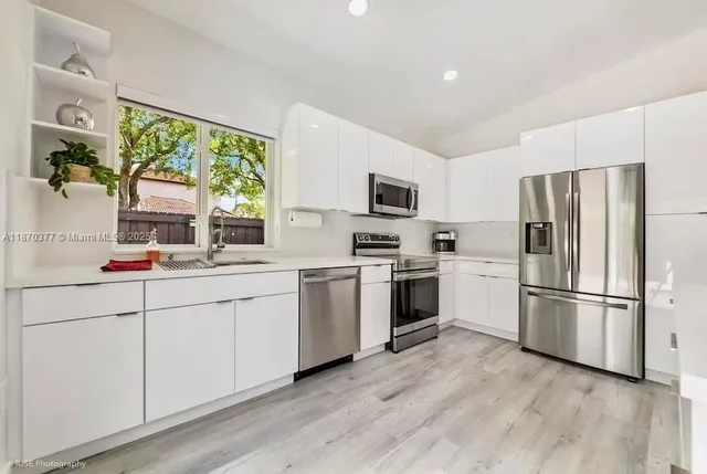 a kitchen with white cabinets and stainless steel appliances