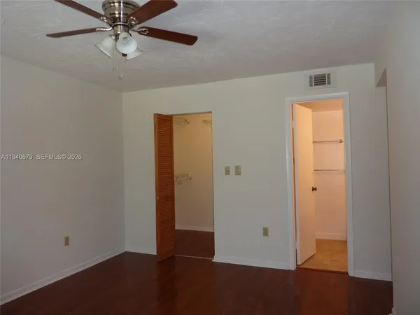 an empty room with wooden floor closet and windows