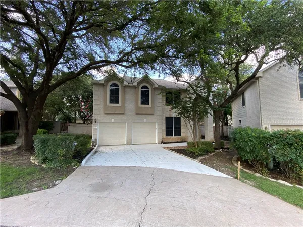 a front view of a house with yard and trees