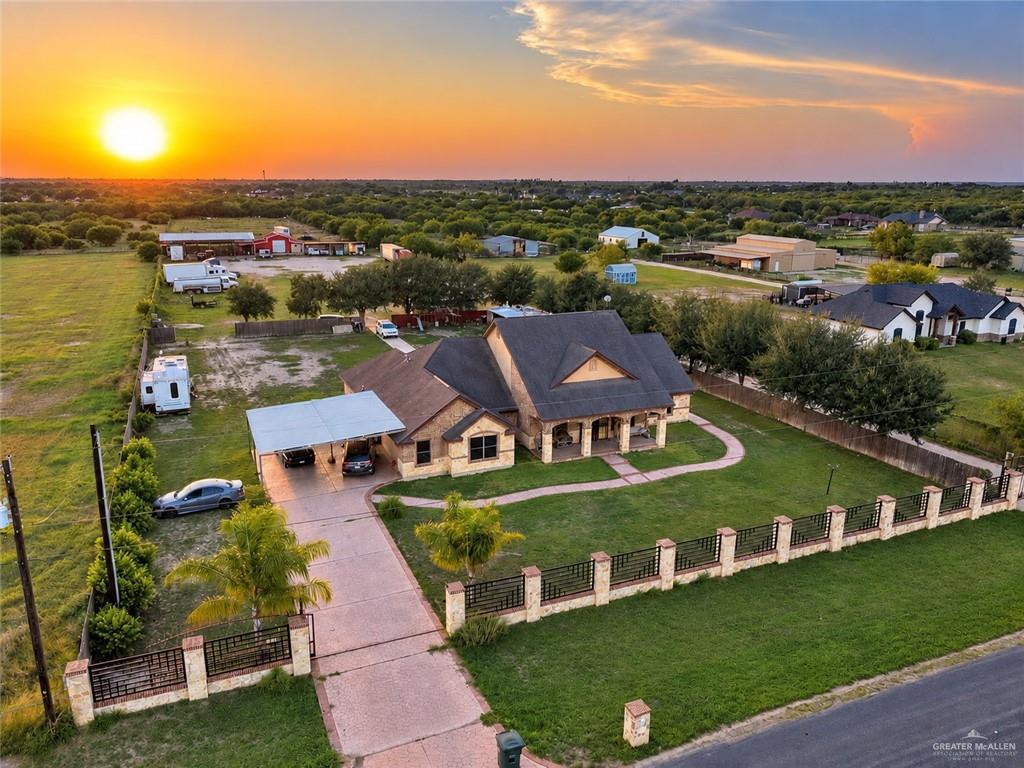 22811 Skinner Road Edcouch, TX 78538 - Photo 2 of 38 Stone-clad exterior, front lawn with mature landscaping, covered front porch, paved driveway with carport, and decorative perimeter fencing