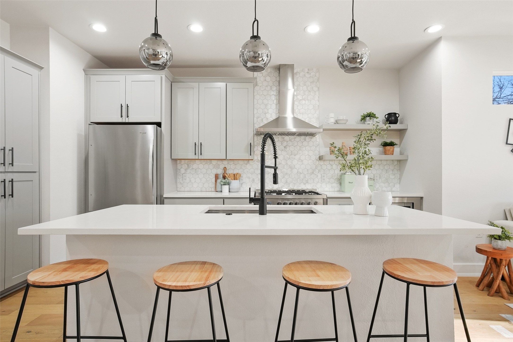 5109 Stone Gate Drive, Unit 2 Austin, TX 78721 - Photo 5 of 36 Contemporary kitchen featuring a white countertop island, stainless steel appliances, light gray cabinetry, honeycomb tile backsplash, and three pendant lights