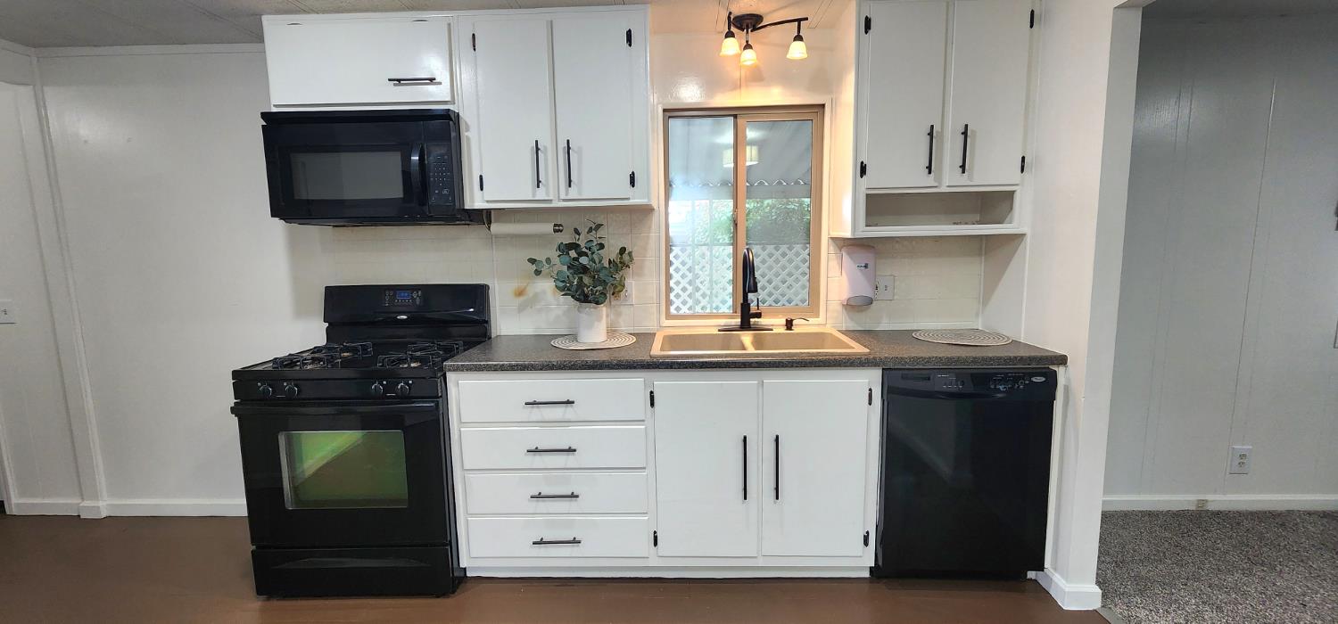 1300 West Olson Avenue, Unit 179 Reedley, CA 93654 - Photo 33 of 39 a kitchen with granite countertop white cabinets and black appliances