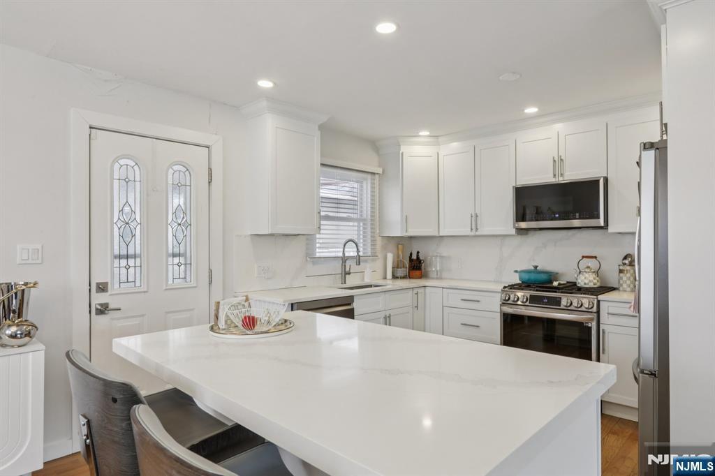 10 Millo Place, Unit 1 Little Ferry, NJ 07643 - Photo 15 of 42 a kitchen with a sink a stove a refrigerator and white cabinets