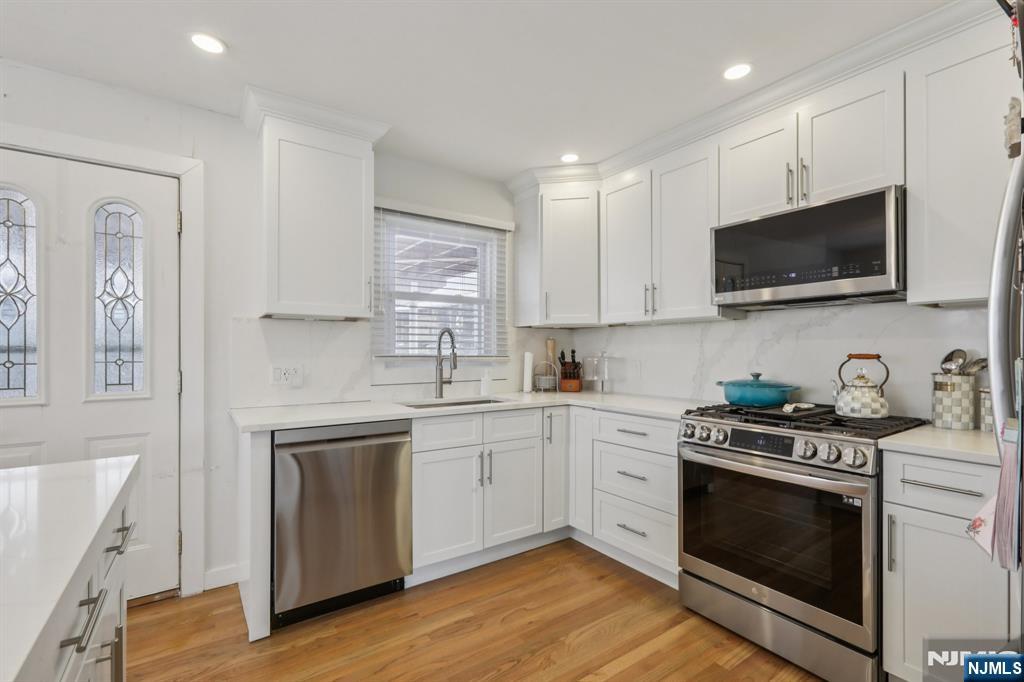 10 Millo Place, Unit 1 Little Ferry, NJ 07643 - Photo 19 of 42 a kitchen with stainless steel appliances granite countertop a stove top oven a sink dishwasher and white cabinets with wooden floor