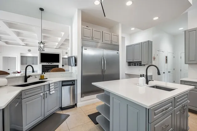 a kitchen with stainless steel appliances a sink dishwasher a refrigerator and a stove with wooden floor