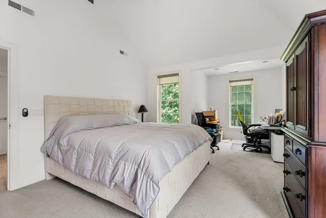 a bedroom with a bed flat screen tv and windows