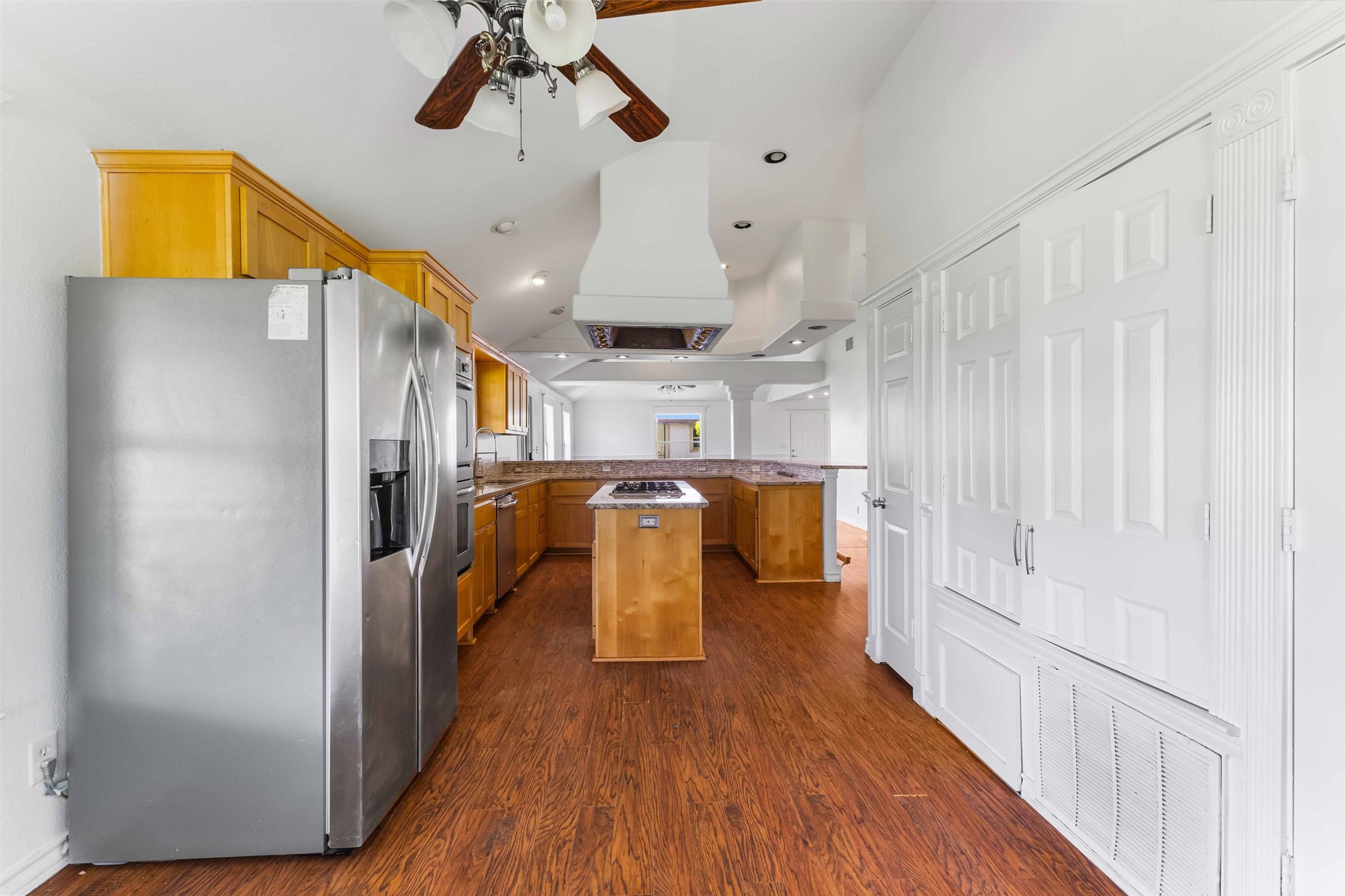 12212 Ballerstedt Road Elgin, TX 78621 - Photo 14 of 39 Kitchen with a peninsula, stainless steel appliances, a center island, a ceiling fan, and wood finish cabinets