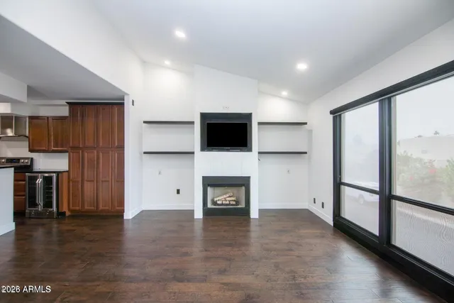 a view of a livingroom with a fireplace and a kitchen space