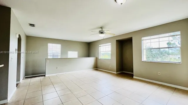 a view of an empty room with window and chandelier fan