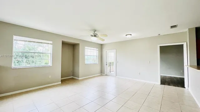 a view of an empty room with window and a chandelier fan