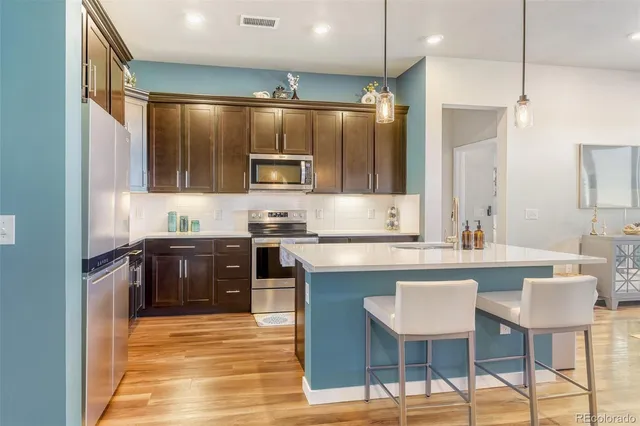 a kitchen with kitchen island granite countertop a sink and a refrigerator