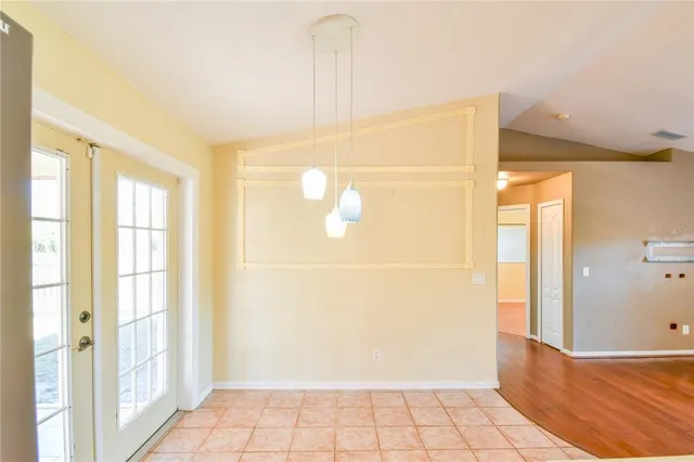 a view of an empty room with wooden floor and a ceiling fan