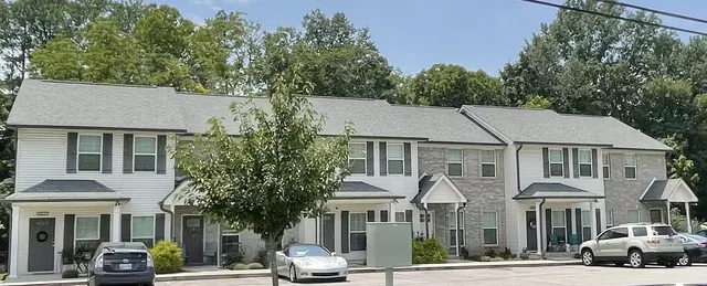 a front view of a residential apartment building with a yard and potted plants