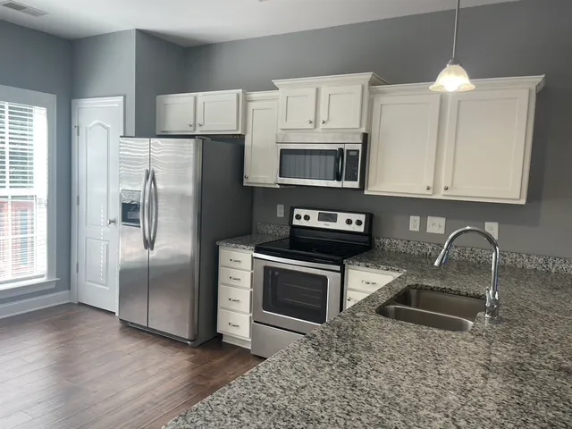 a kitchen with stainless steel appliances granite countertop a refrigerator microwave and sink