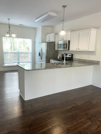 a large kitchen with granite countertop a stove a sink a window and wooden floor