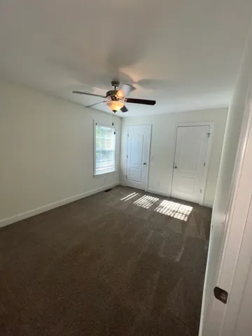 en empty room with windows and ceiling fan