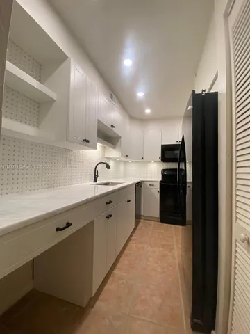 a large kitchen with a sink stainless steel appliances and cabinets