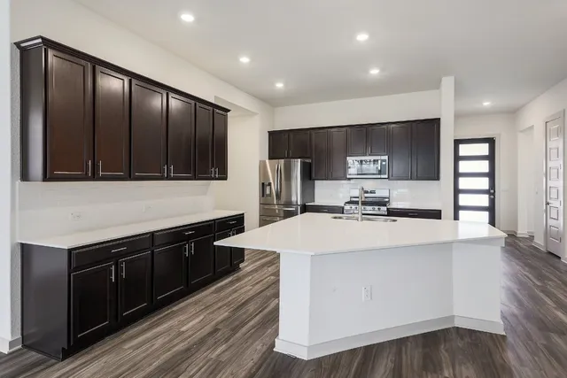 a large kitchen with stainless steel appliances wooden cabinets and a wooden floor