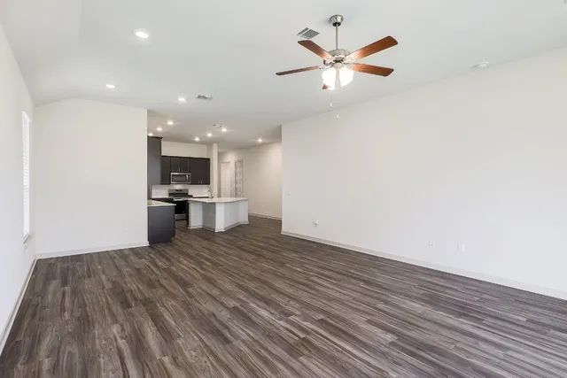 a view of kitchen and empty room with wooden floor