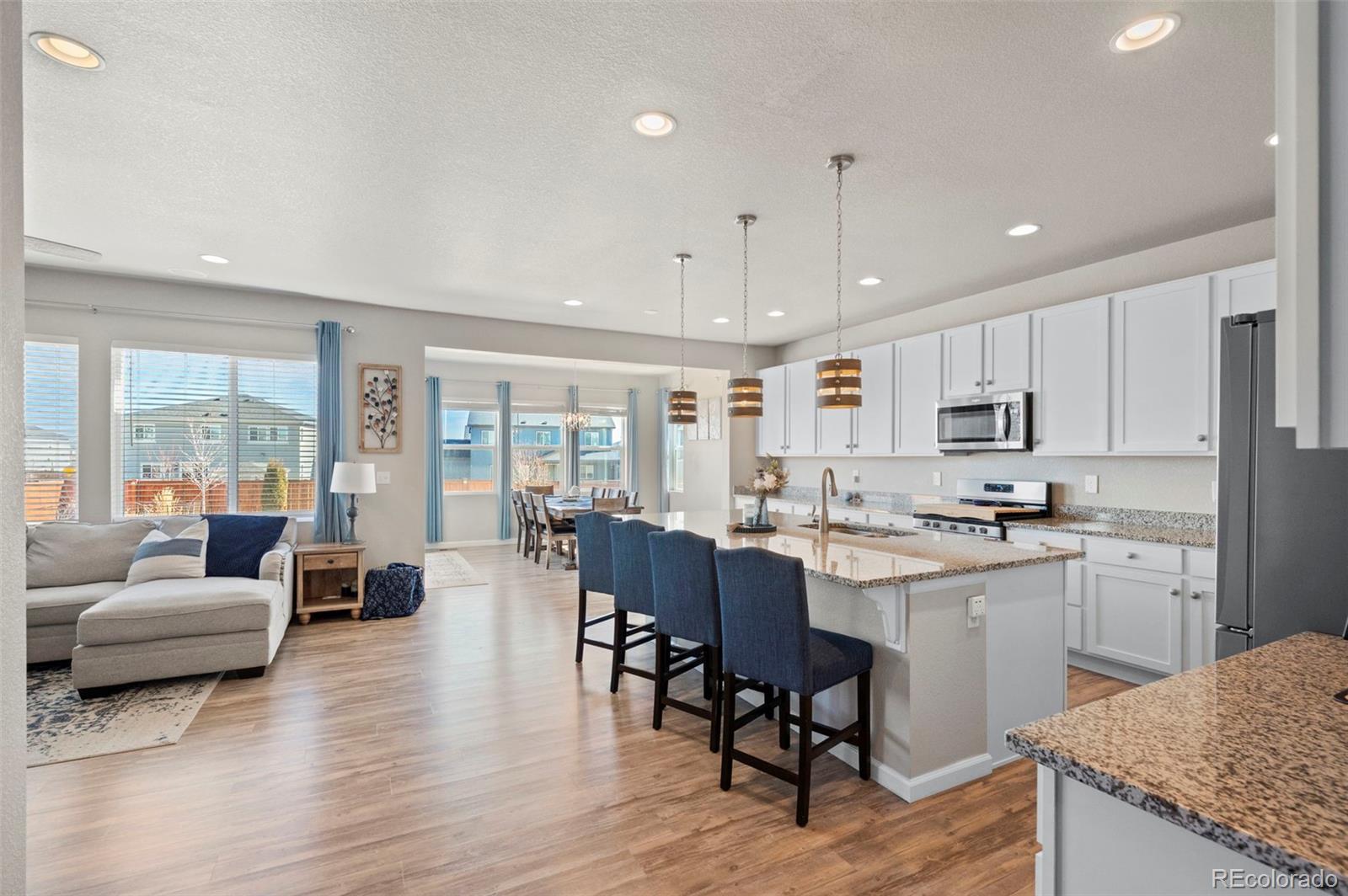 11778 Oneida Street Thornton, CO 80233 - Photo 6 of 30 a large kitchen with cabinets chairs and wooden floor