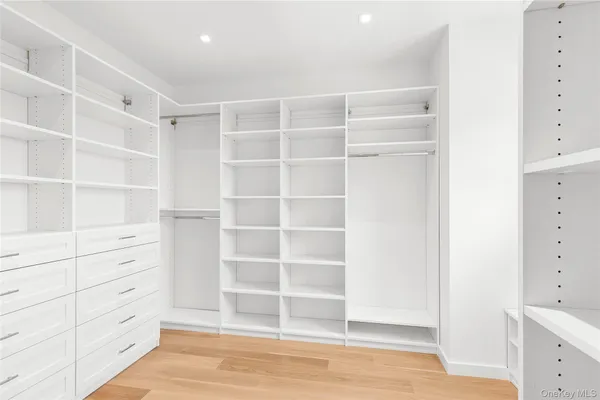 a view of an empty room with wooden floor and closet