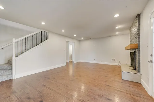 a view of a hallway with wooden floor and a kitchen