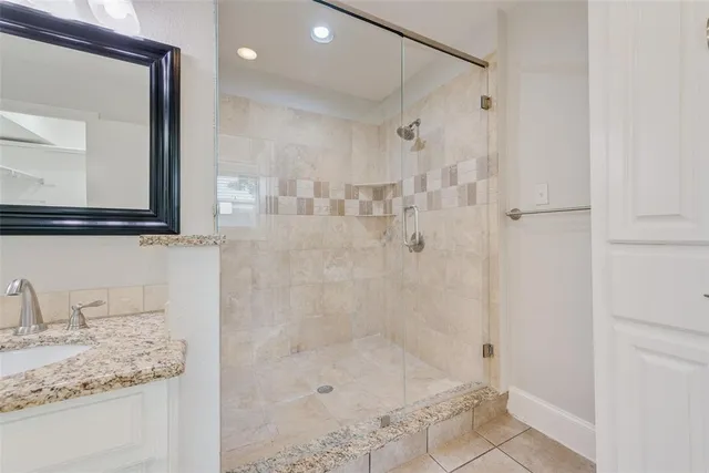 a bathroom with a granite countertop sink a mirror and shower