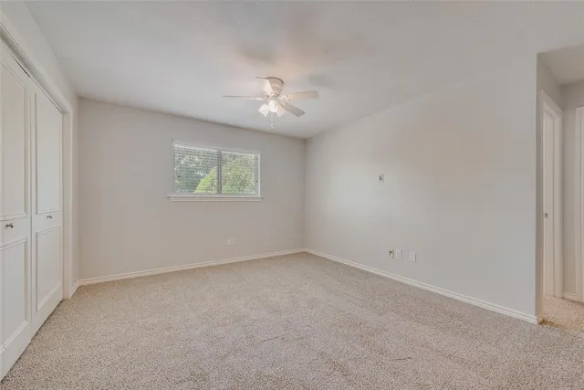 an empty room with a window and a ceiling fan