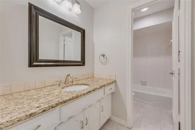 a bathroom with a granite countertop sink two mirror and a bathtub