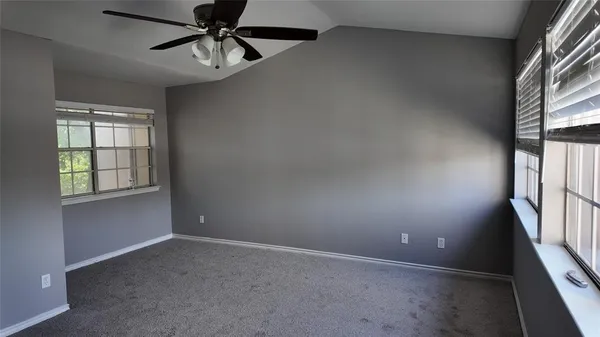 an empty room with windows and fan