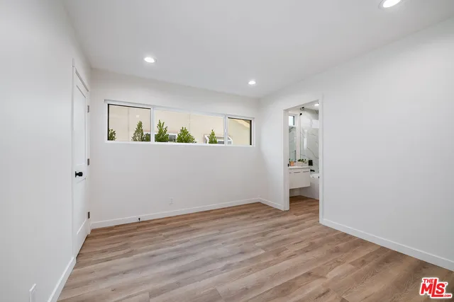 a view of an empty room with wooden floor and closet