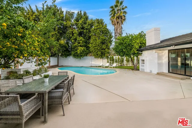 a patio with table and chairs and potted plants