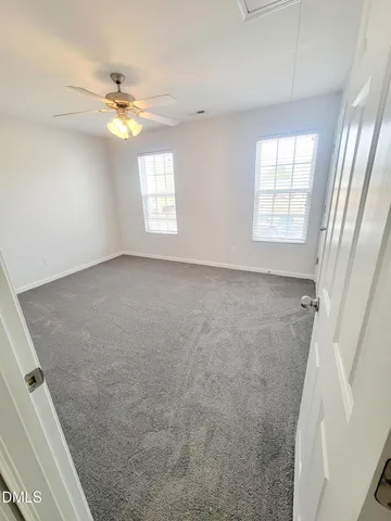 an empty room with windows and chandelier fan