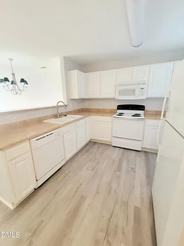 a kitchen with a sink a stove a refrigerator and white cabinets
