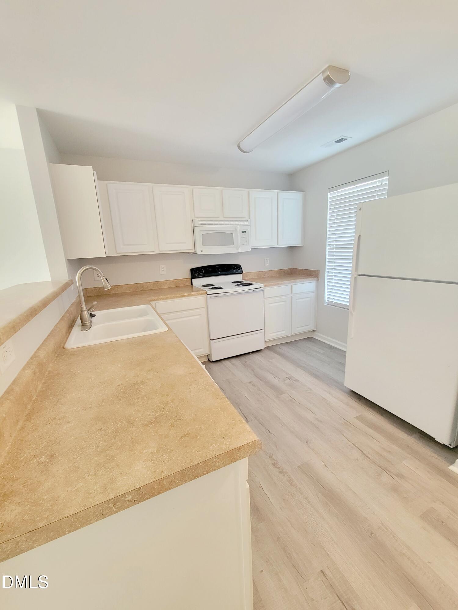 1407 Plexor Lane Knightdale, NC 27545 - Photo 5 of 43 a kitchen with a sink a stove a refrigerator and white cabinets