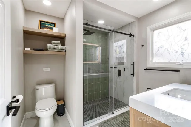 a bathroom with a window a toilet and a shower