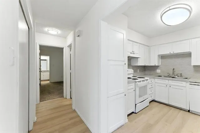 a kitchen with white cabinets and sink