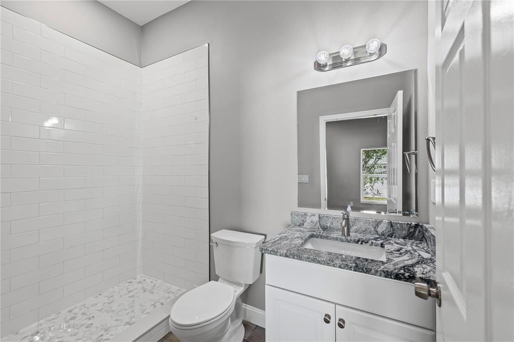 5046 99th Way North St. Petersburg, FL 33708 - Photo 17 of 41 a bathroom with a granite countertop sink mirror vanity and toilet