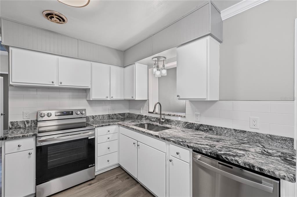 5046 99th Way North St. Petersburg, FL 33708 - Photo 9 of 41 a kitchen with granite countertop a stove sink and cabinets