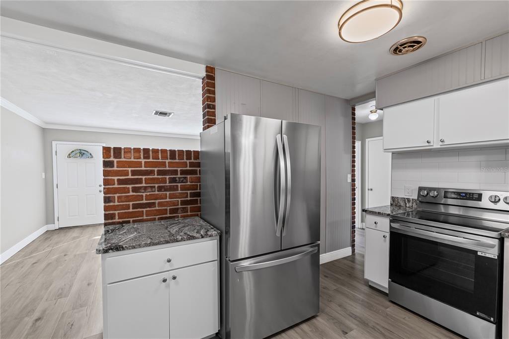 5046 99th Way North St. Petersburg, FL 33708 - Photo 10 of 41 a kitchen with granite countertop a refrigerator and a stove top oven