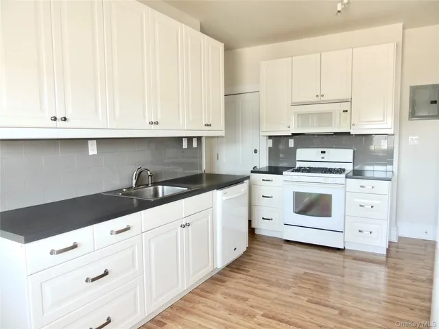 a kitchen with granite countertop white cabinets and white appliances