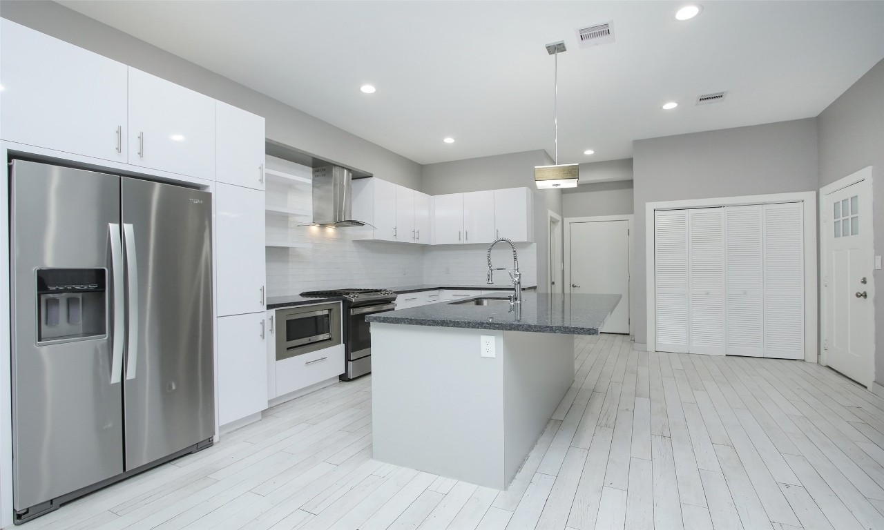 309 East 43rd Street, Unit A Houston, TX 77022 - Photo 13 of 35 a kitchen with stainless steel appliances granite countertop a refrigerator a sink dishwasher a stove and a refrigerator with wooden floor