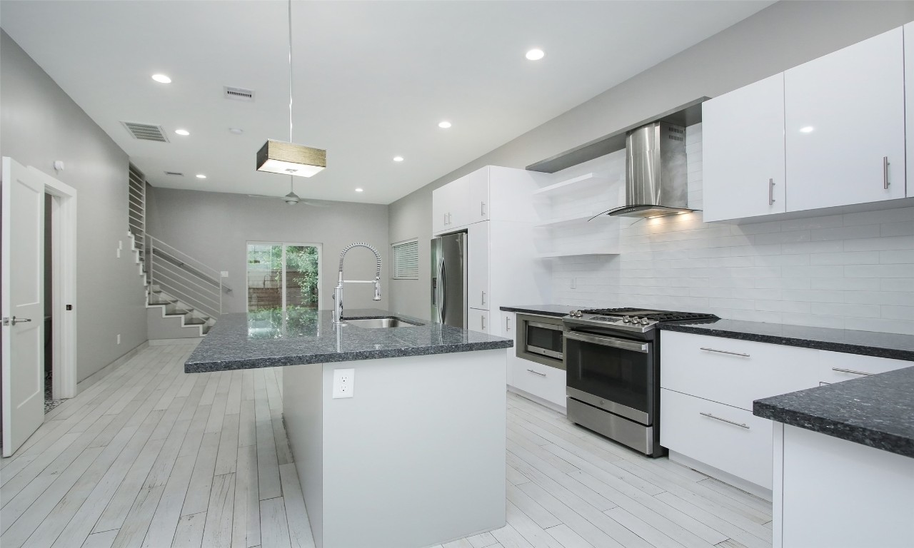 309 East 43rd Street, Unit A Houston, TX 77022 - Photo 10 of 35 a large kitchen with stainless steel appliances granite countertop a stove and a wooden floors