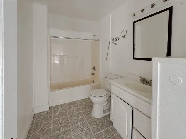 a bathroom with a granite countertop toilet a sink and a mirror